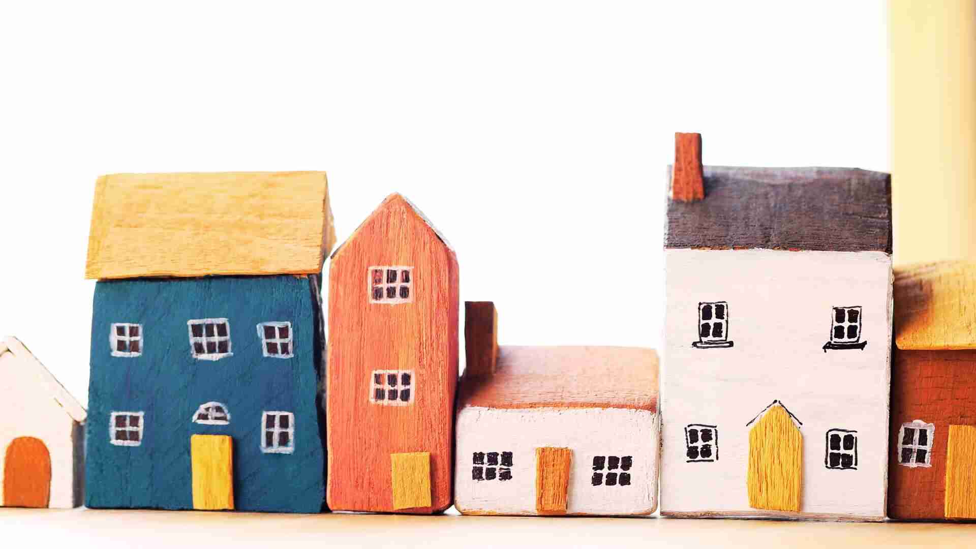 Reihe von bunten Holzhausmodellen in verschiedenen Farben und Formen auf einem hellen Hintergrund.